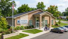 Brick Kingdom Hall of Jehovah's Witnesses building with flagpole and family walking outside